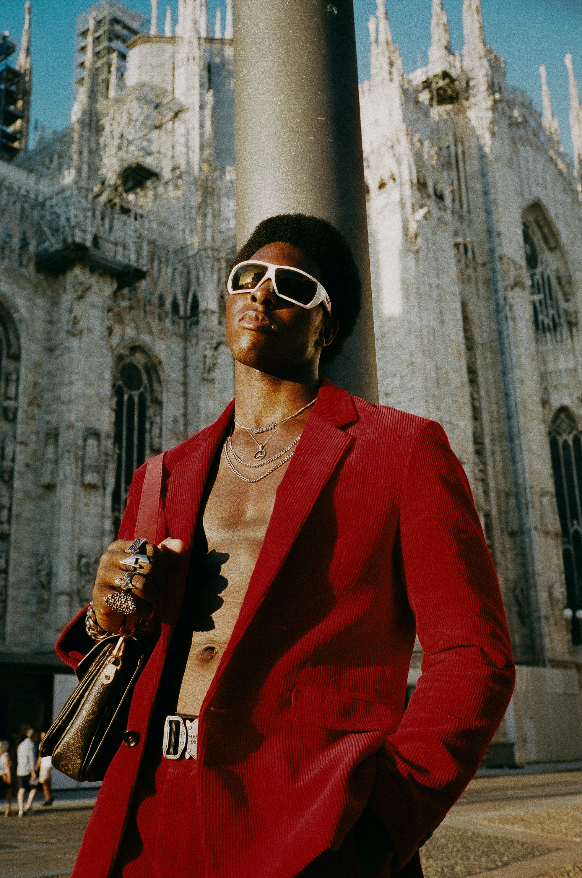 Editorial portrait of a model in a red corduroy jacket outside Milan's Duomo.